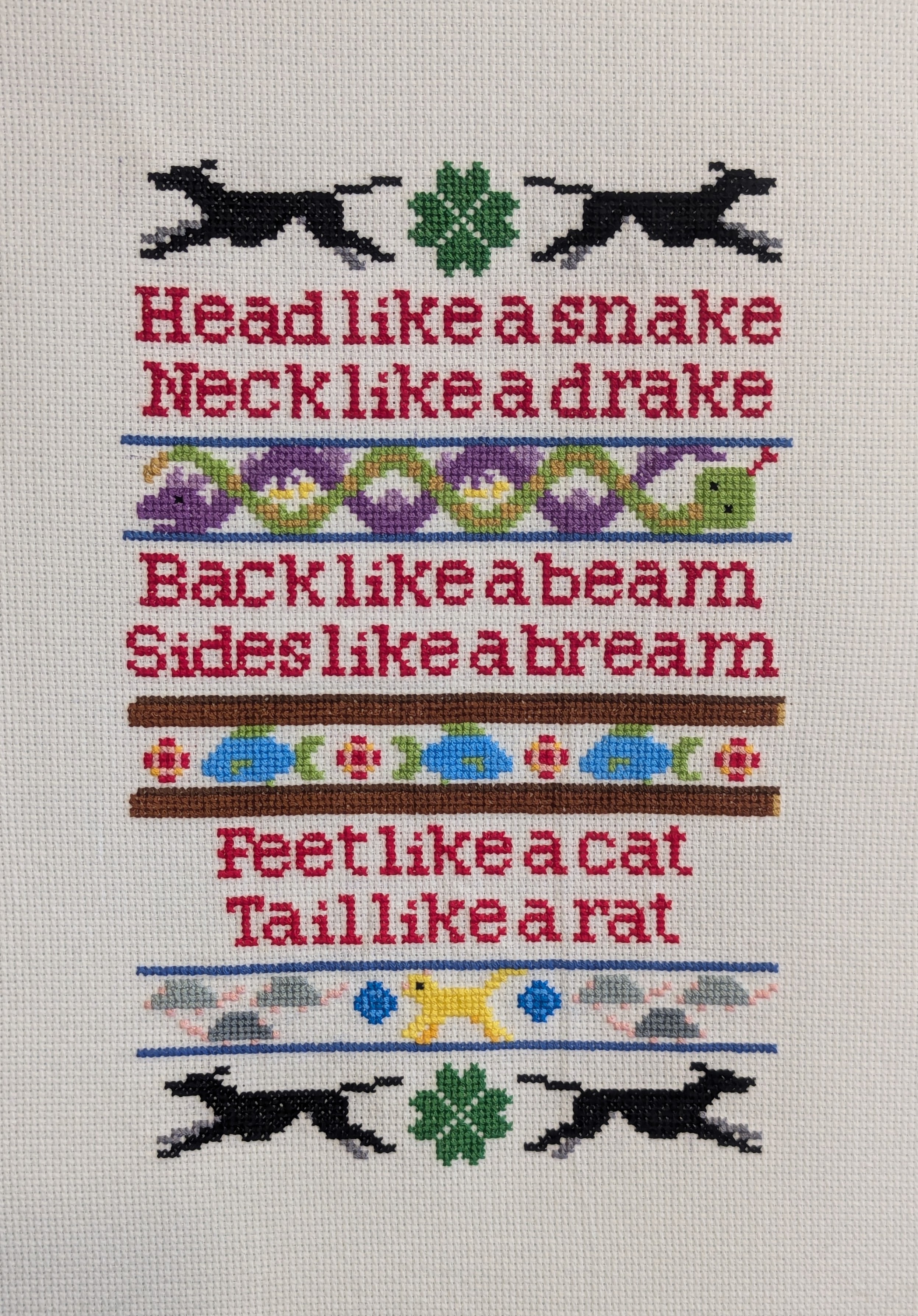 Cross stitch sampler with running greyhounds that reads 'head like a snake, neck like a drake, back like a beam, sides like a bream, feet like a cat, tail like a rat'