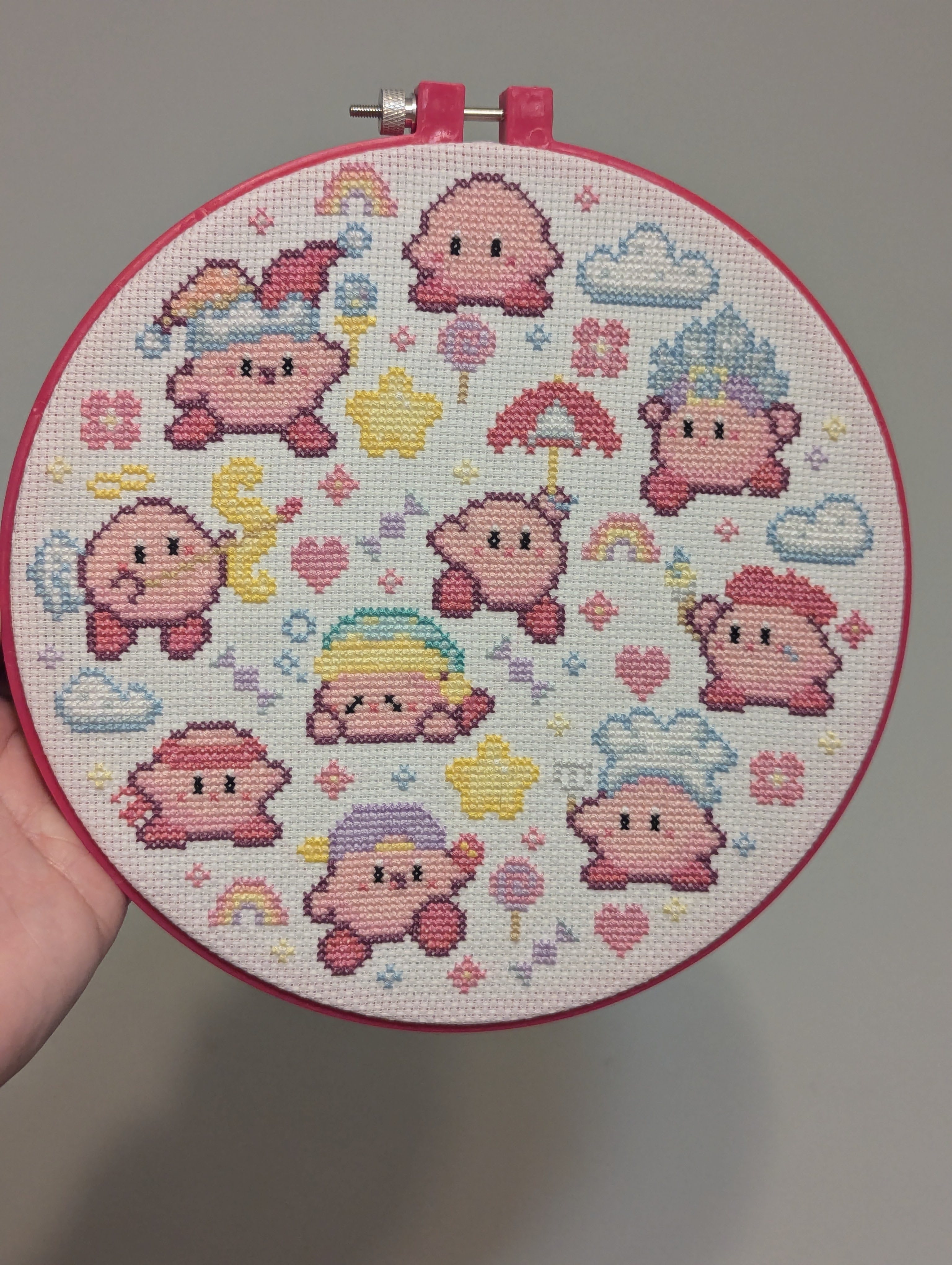 Cross stitch of several iterations of kirby's powers and outfits, arranged loosely in a circle