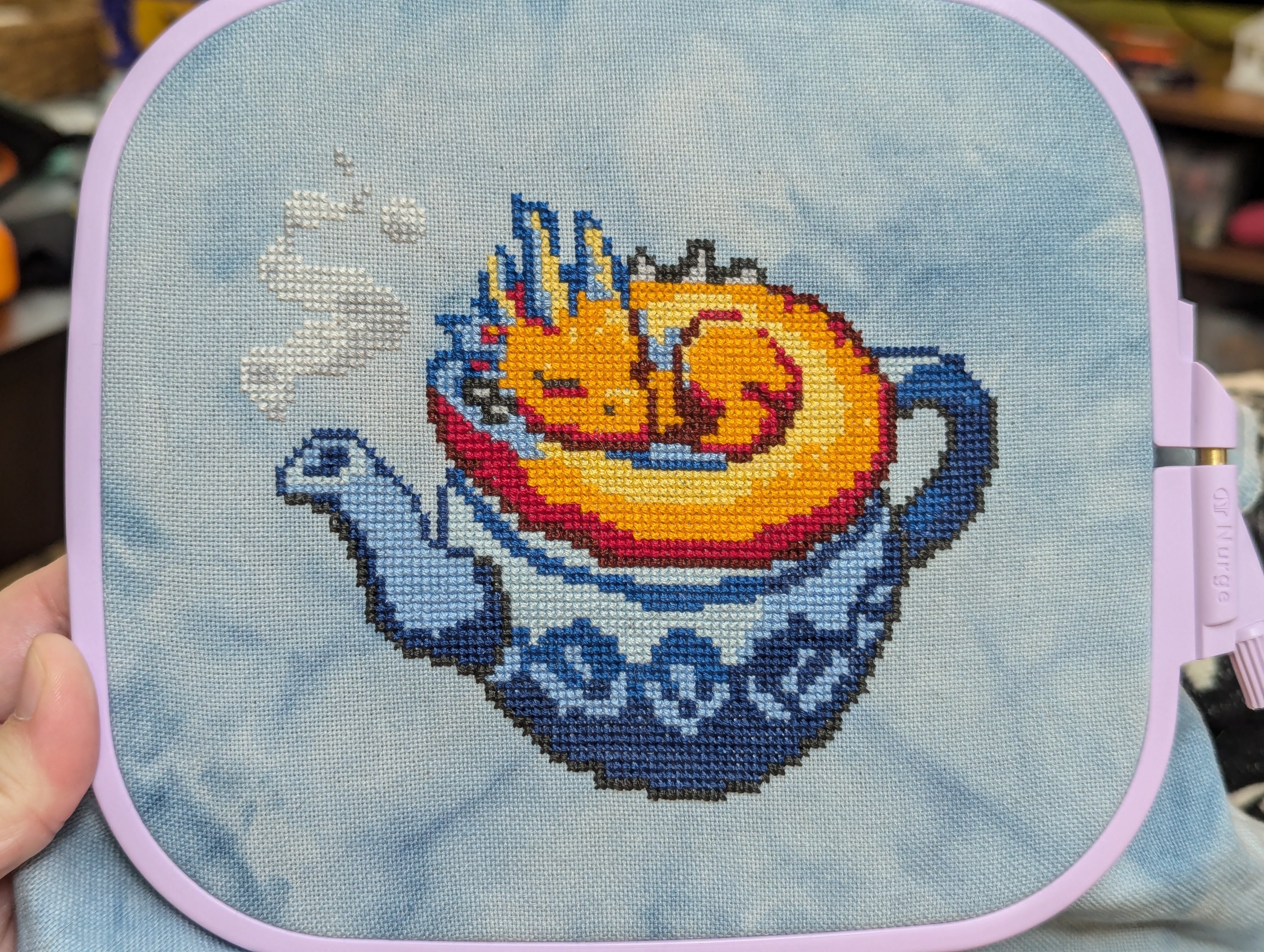 Cross stitch of gingerbread house with a scream skull on it